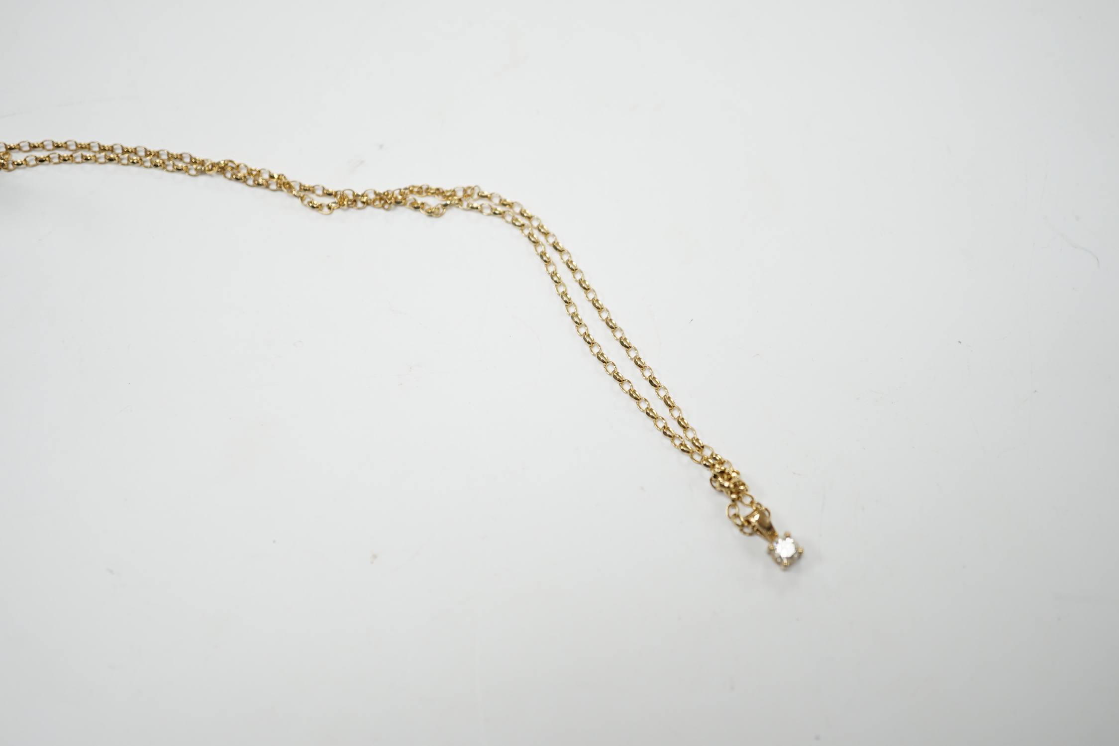 A modern 9ct gold and solitaire diamond set pendant, 9mm, on a 9ct chain, 38cm, gross weight 2.2 grams.